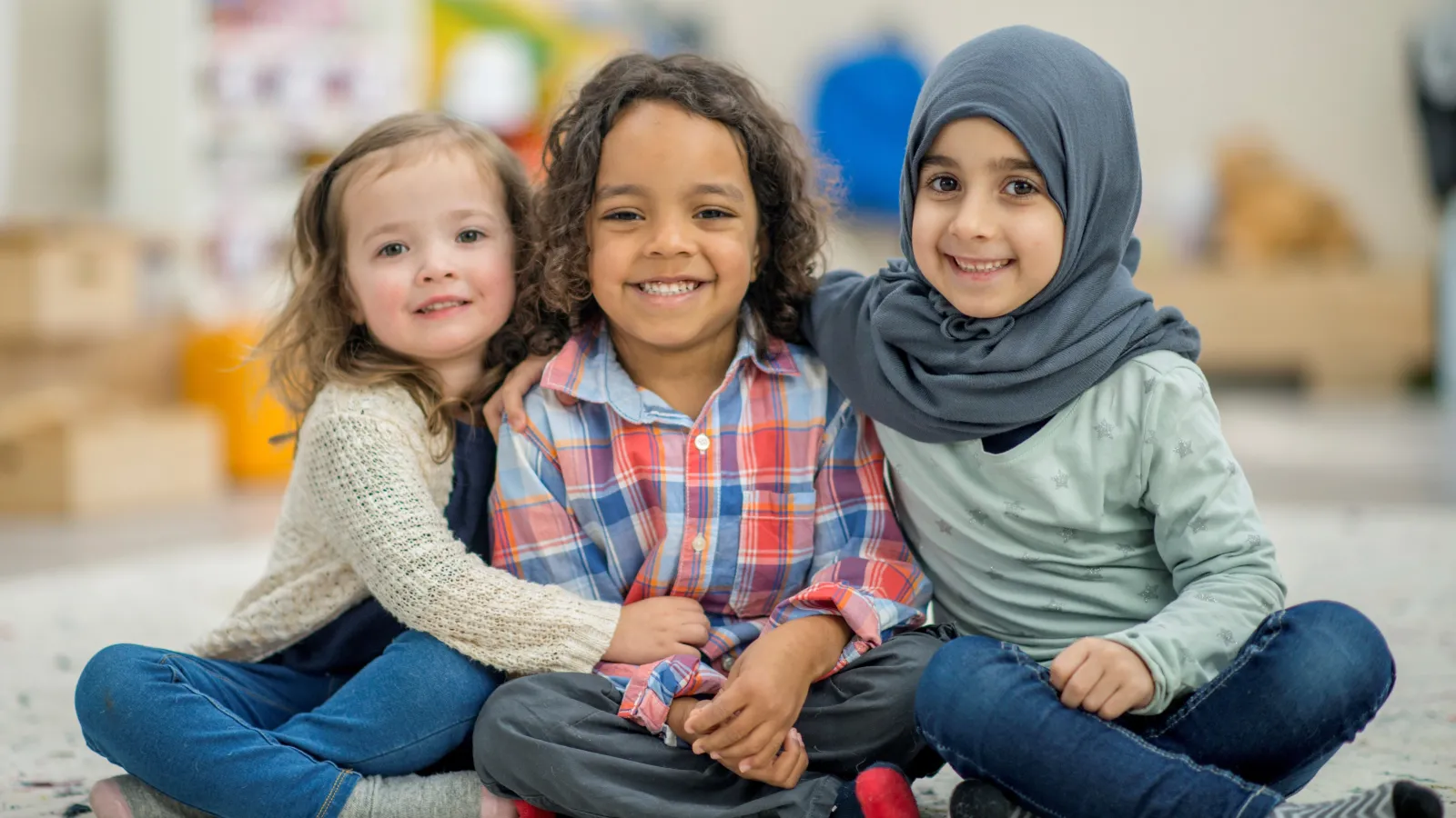 Three preschool children sitting on the floor